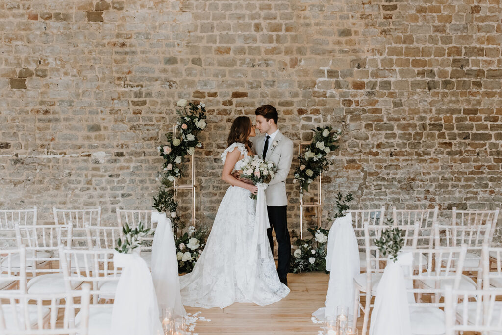 Bride and groom during wedding ceremony with floral arch, candles and draping fabric | Louise Hayes Cake Design | Melissa Megan Photography | Cowdray Wedding