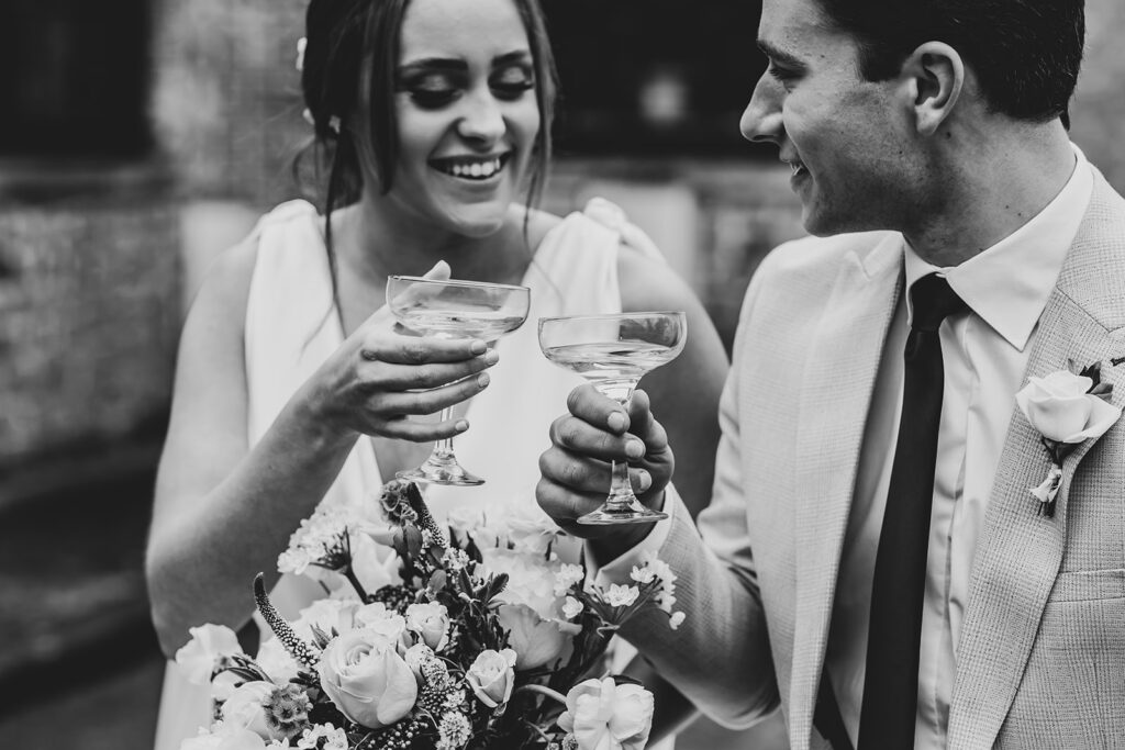 Bride and groom with champagne in 1968 Triumph | Louise Hayes Cake Design | Melissa Megan Photography | Cowdray Wedding