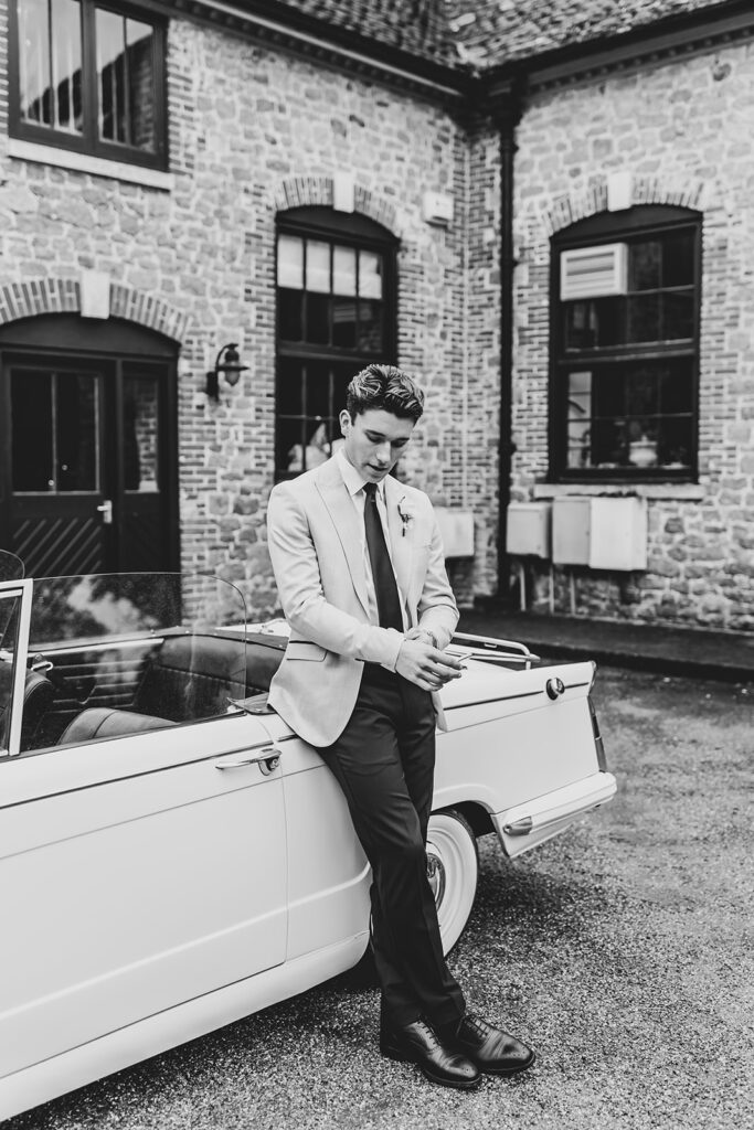 Groom leaning against a 1968 Triumph | Louise Hayes Cake Design | Melissa Megan Photography | Cowdray Wedding