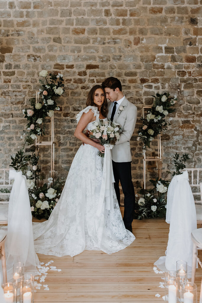 Bride and groom during wedding ceremony with floral arch, candles and draping fabric | Louise Hayes Cake Design | Melissa Megan Photography | Cowdray Wedding